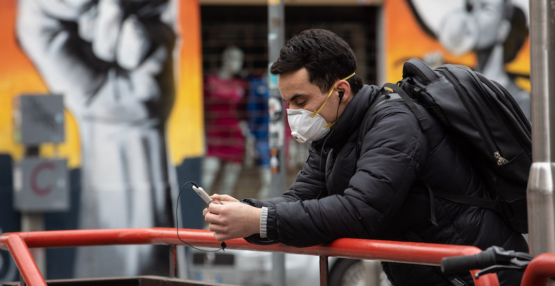 Un uomo legge dal proprio smartphone nei primi giorni del lockdown a Milano, l'11 marzo 2020. (Emanuele Cremaschi/Getty Images)