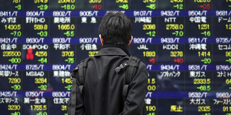 Un uomo davanti a un tabellone elettronico che mostra i titoli azionistici in Giappone (AP Photo/Eugene Hoshiko)