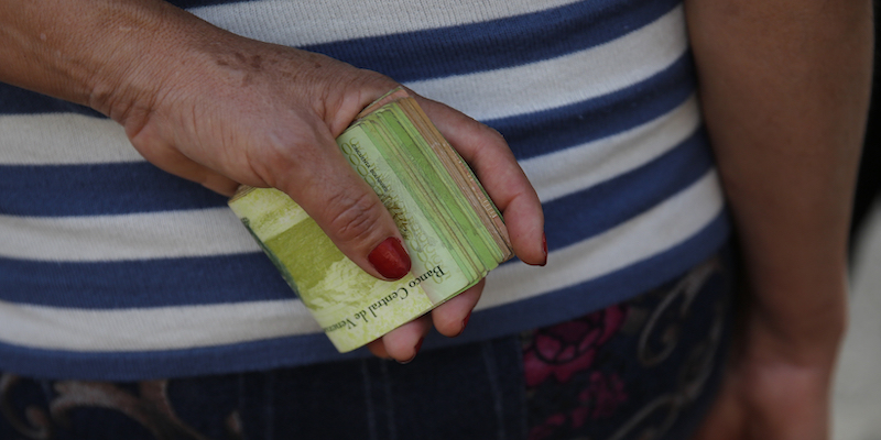 Una persona in Venezuela con in mano una mazzetta di contanti (AP Photo/Ariana Cubillos)