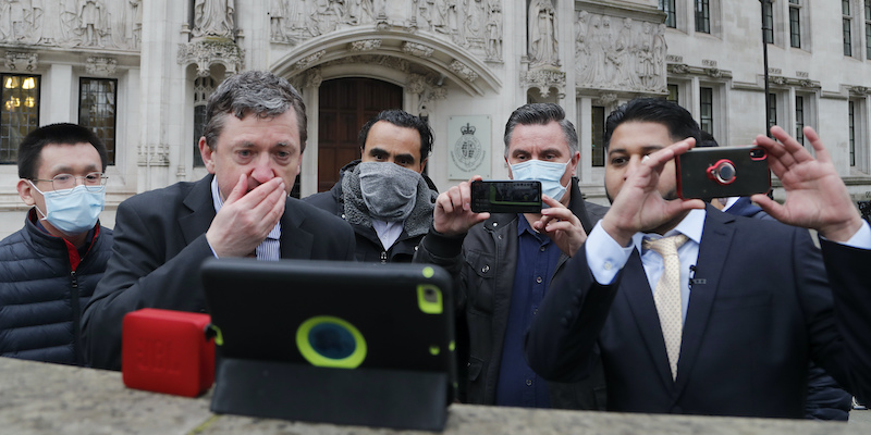 Alcuni conducenti di Uber seguono su un telefono la decisione della Corte Suprema di Londra, il 19 febbraio 2021 (AP Photo/Frank Augstein)