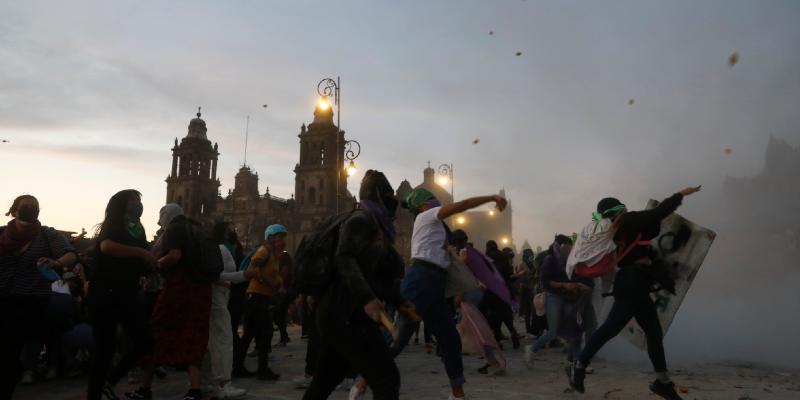 Alcune manifestanti lanciano sassi verso il Palazzo Nazionale di Città del Messico, 8 marzo 2021. (AP Photo/ Rebecca Blackwell)