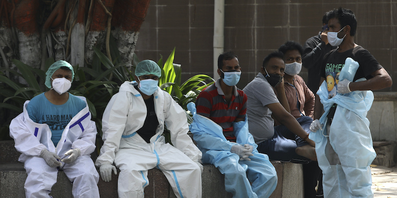 Alcuni operatori sanitari in una pausa dal lavoro di cremazione di persone morte per COVID-19 a Nuova Delhi, la capitale dell'India, il 19 aprile 2021 (AP Photo/Manish Swarup)