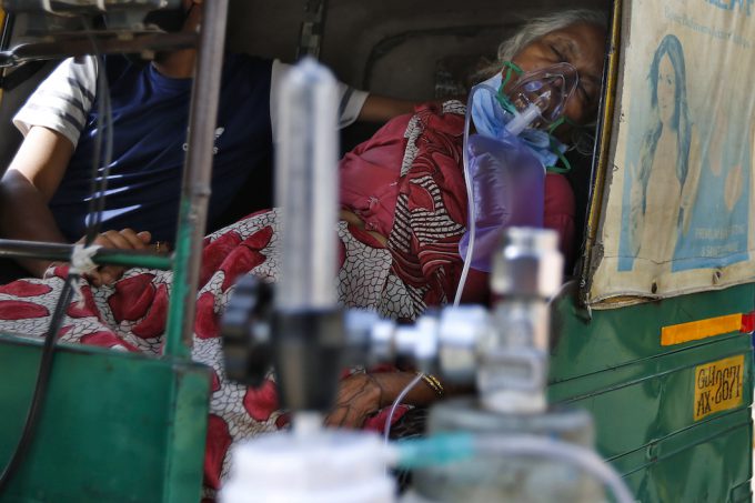 Un donna malata di COVID-19 respira con l'aiuto di una maschera di ossigeno in un risciò, attende di essere ricoverata in ospedale, ad Ahmedabad, in India (AP / Ajit Solanki) 