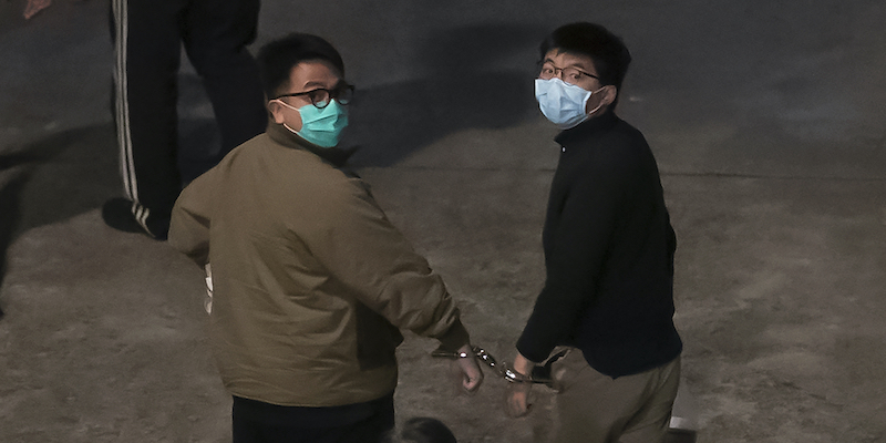 Joshua Wong, a destra, insieme a un altro attivista di Hong Kong, Ivan Lam, durante il loro arresto il 2 dicembre del 2020 (AP Photo/Kin Cheung)