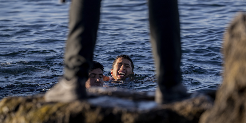 Due migranti cercano di raggiungere la spiaggia di Ceuta a nuoto sorvegliati da un poliziotto spagnolo, lo scorso 19 maggio (AP Photo/Bernat Armangue)