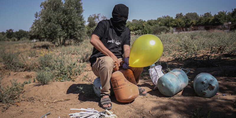 Un miliziano di un gruppo armato dei Comitati Popolari di Resistenza di Gaza mentre prepara un palloncino incendiario, il 16 giugno (Fatima Shbair/Getty Images)