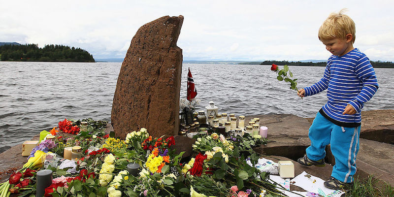 Un bambino lascia un fiore su una banchina nei pressi dell'isola di Utøya (Jeff J Mitchell/Getty Images)
