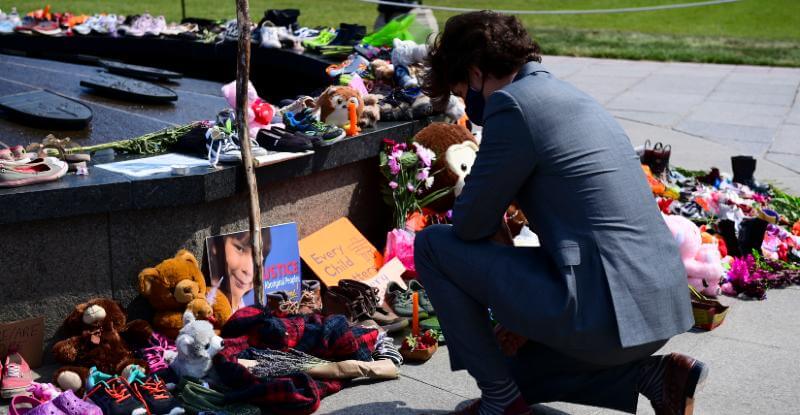 Il primo ministro canadese, Justin Trudeau, si inginocchia davanti al memoriale allestito a Parliament Hill, a Ottawa, dopo la scoperta della fossa comune coi resti di 215 bambini indigeni di fine maggio. Primo giugno 2021 (Sean Kilpatrick/ The Canadian Press via AP, File)