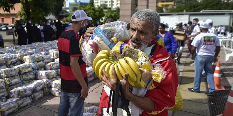 Un uomo trasporta cibo distribuito gratuitamente da una banca di Belo Horizonte, in Brasile. (Pedro Vilela/Getty Images)