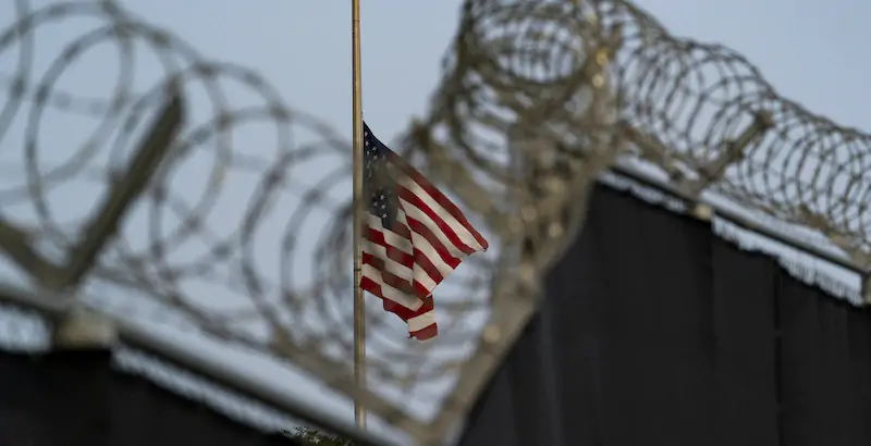 Un'immagine della bandiera americana vista attraverso il filo spinato della prigione di Guantanamo (AP Photo/Alex Brandon, File)