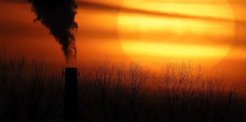 Emissions from a coal-fired power plant are silhouetted against the setting sun, Monday, Feb. 1, 2021, in Independence, Mo. (AP Photo/Charlie Riedel)