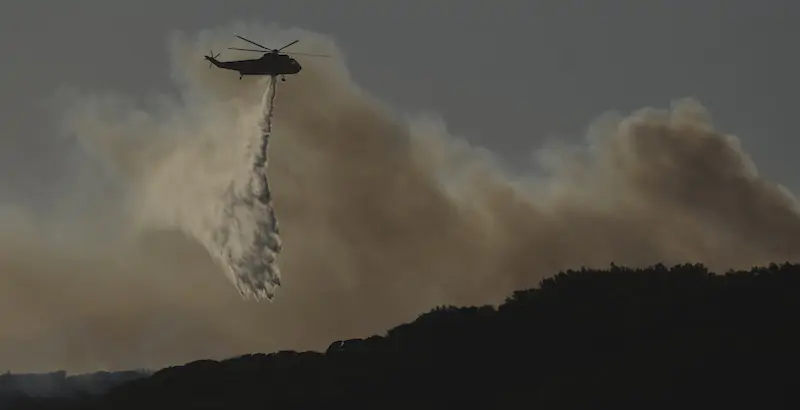 Un elicottero impegnato nello spegnimento di un incendio, in California (AP Photo/Ringo H.W. Chiu)