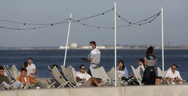 Persone sedute a un bar sul fiume Tago, a Lisbona (AP Photo/ Armando Franca, File)