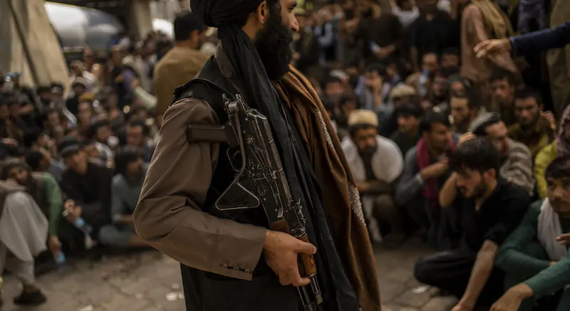 Un miliziano talebano armato cerca di controllare decine di persone che si accalcano davanti a una banca per ritirare denaro (AP Photo/Bernat Armangue)