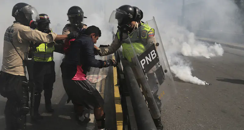 Alcuni poliziotti venezuelani strattonano un manifestante a Caracas, durante le proteste del 2017 (AP Photo/Fernando Llano)