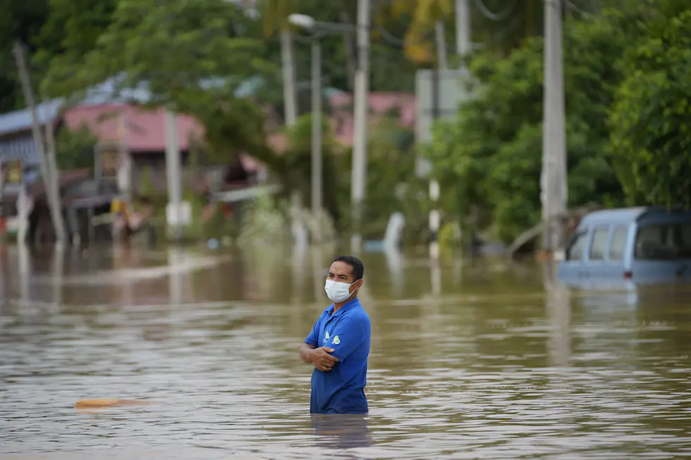 Un uomo attraversa una strada allagata a Hulu Langat, nella periferia di Kuala Lumpur, in Malesia. Kuala Lumpur è stata colpita da inondazioni causate da due giorni di forti piogge, che hanno costretto migliaia di residenti a lasciare le proprie case. (AP Photo/Vincent Thian)