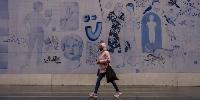 Una donna cammina davanti a un murale a Madrid (AP Photo/ Manu Fernandez)