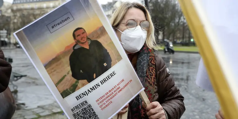 Una donna con una foto di Benjamin Brière durante una manifestazione organizzata a sostegno di quest'ultimo a Parigi, in Francia (AP Photo/Adrienne Surprenant)