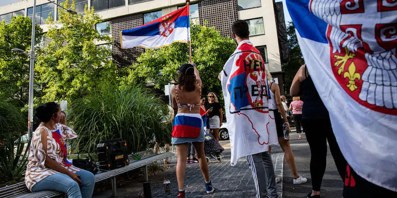 Alcune persone sventolano la bandiera serba nei pressi del Park Hotel di Melbourne, dove in questi giorni è alloggiato Novak Djokovic (Diego Fedele/Getty Images)