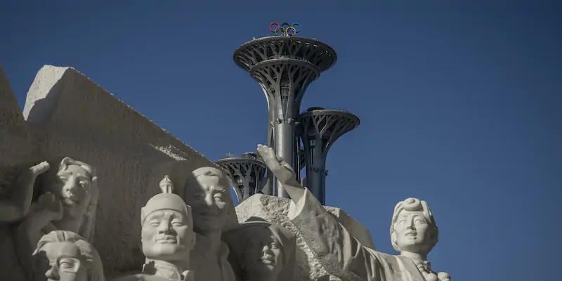 La fiamma olimpica di Pechino dietro a una scultura della rivoluzione comunista cinese (Andrea Verdelli/Getty Images)