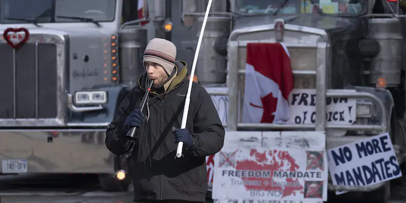 Un uomo che protesta a Ottawa, di fronte ad alcuni camion, l'1 febbraio 2022 (THE CANADIAN PRESS/Adrian Wyld via AP)
