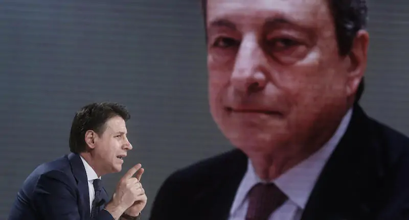 Il leader del Movimento 5 Stelle, Giuseppe Conte, e sullo sfondo una foto del presidente del Consiglio, Mario Draghi (ANSA/FABIO FRUSTACI)