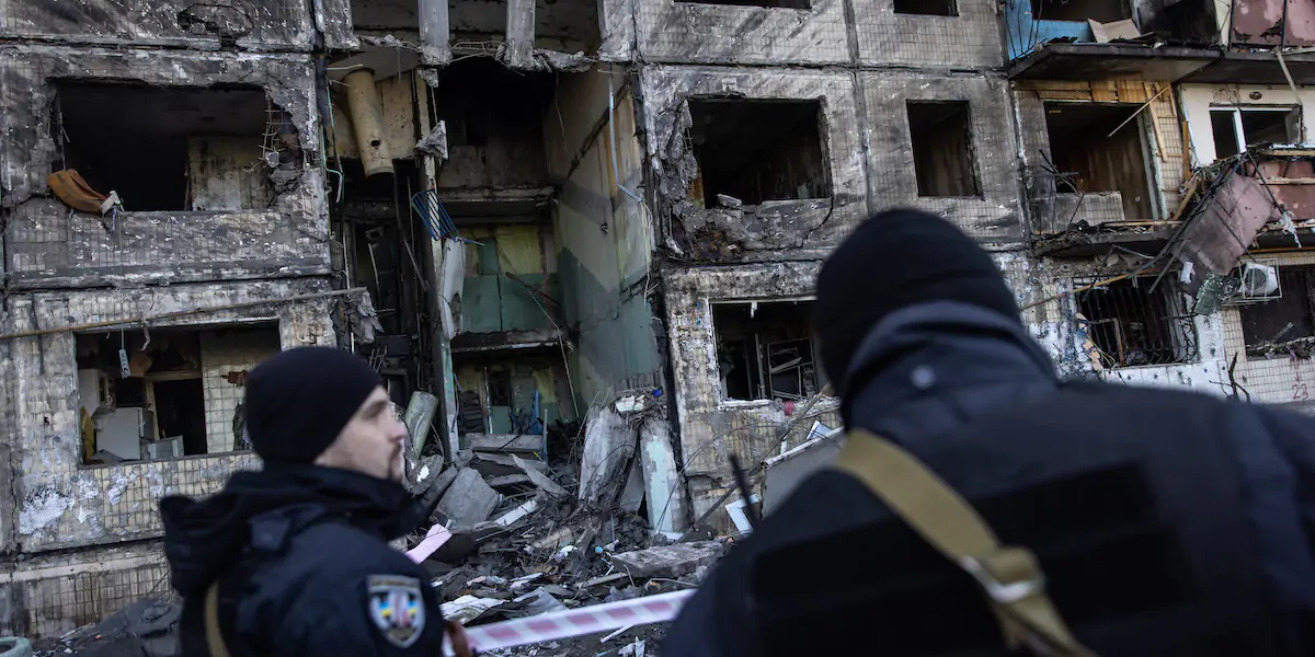 Una coppia di poliziotti ucraini di fronte a un condominio di Kiev colpito dai russi, il 14 marzo 2022 (Chris McGrath/Getty Images)