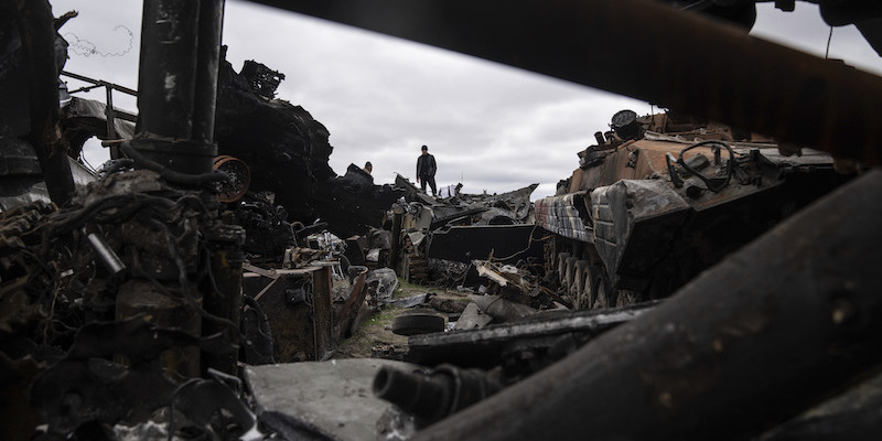 Un uomo in piedi tra veicoli militari distrutti a Bucha, nella periferia di Kiev (AP Photo/Evgeniy Maloletka)