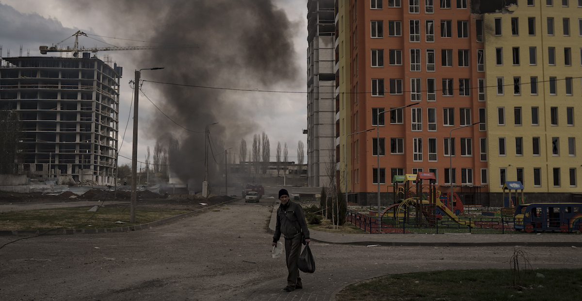 Una persona accanto a un incendio provocato da un bombardamento a Kharkiv, Ucraina, 21 aprile (AP Photo/ Felipe Dana)