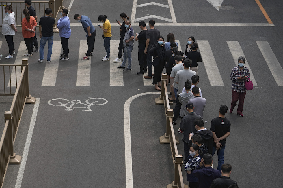 Persone in fila per sottoporsi al test, nel distretto di Chaoyang (AP Photo/Andy Wong)