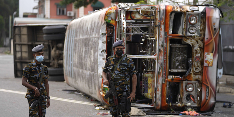 Forze di sicurezza dello Sri Lanka vicino ad alcuni autobus incendiati dai manifestanti (AP Photo/Eranga Jayawardena)