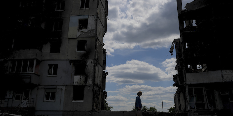 Una donna fotografata vicino ad alcuni edifici distrutti a Borodyanka, alla periferia di Kiev, nelle prime settimane di guerra (AP Photo/Natacha Pisarenko)