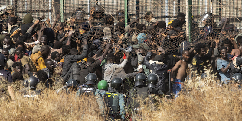 Un gruppo di migranti cerca di scavalcare le barriere per entrare a Melilla, venerdì 24 giugno (AP Photo/ Javier Bernardo)