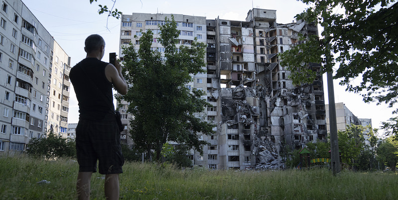 Un uomo riprende un edificio distrutto da un attacco russo a Kharkiv, in Ucraina, il primo luglio 2022 (AP Photo/Evgeniy Maloletka, File)