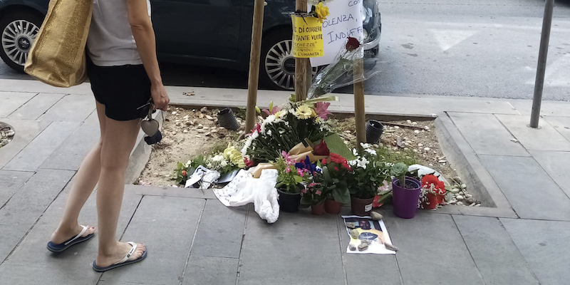 Una donna osserva i fiori deposti sul luogo dell’omicidio di Alika Ogorchukwu, a Civitanova Marche, sabato 30 luglio 2022 (AP/Chiara Gabrielli)