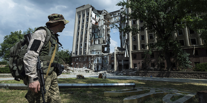 Un soldato ucraino di fronte a un edificio distrutto di Mykolaiv (AP Photo/Evgeniy Maloletka)