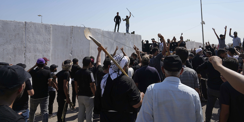 Sostenitori di Muqtada al Sadr che tentano di abbattere le protezioni attorno all'area in cui si trovano gli edifici governativi (AP Photo/Hadi Mizban)