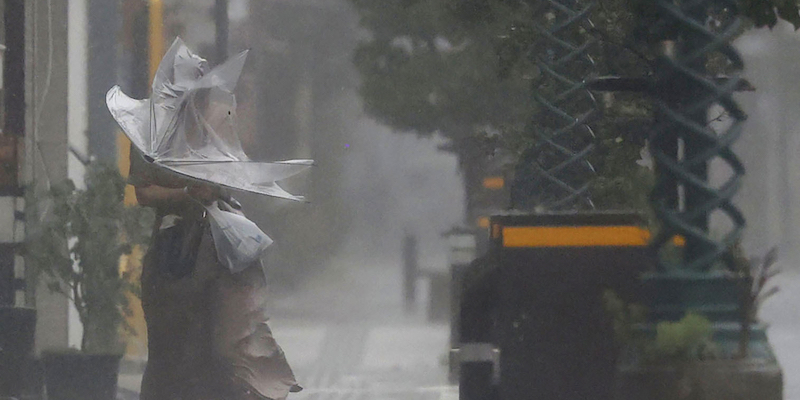 Una donna cammina sotto le forti piogge a Miyazaki, domenica 18 settembre (Kyodo News via AP)
