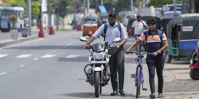 Una persona porta a mano una moto per la mancanza di carburante a Colombo, in Sri Lanka (AP Photo/Eranga Jayawardena, File)