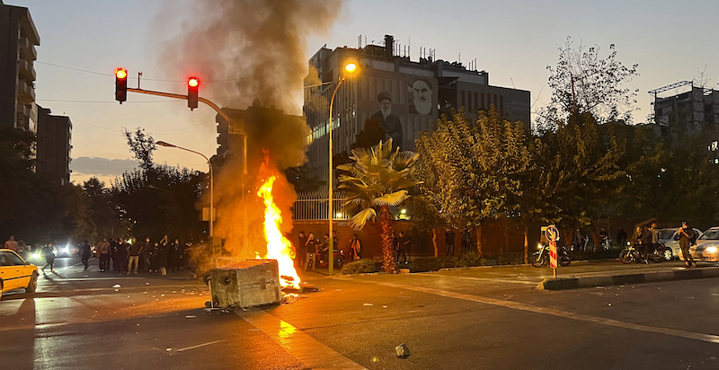 Una moto della polizia e un cassonetto bruciati dai manifestanti a Teheran (AP Photo)