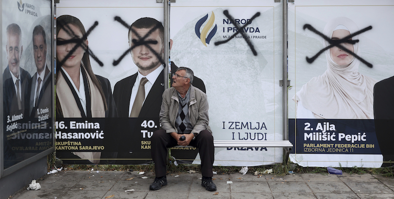 Un uomo aspetta l'autobus davanti ad alcuni manifesti elettorali a Sarajevo (AP Photo/Armin Durgut)