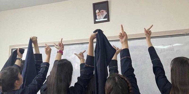 Alcune studentesse mostrano il dito medio a un ritratto della Guida suprema Ali Khamenei (Siavash Ardalan/Twitter)