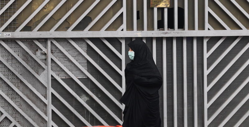 Una donna cammina davanti a un negozio chiuso a Teheran (EPA/STR)