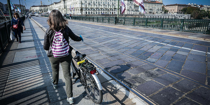 Una persona porta a mano una bici sul ponte Vittorio Emanuele I a Torino, che non si può attraversare in bici (ANSA/TINO ROMANO)