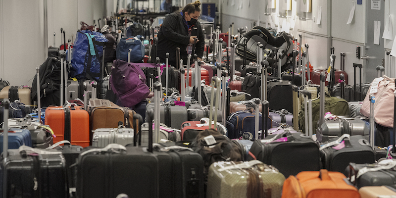 Una dipendente di Southwest Airlines controlla i bagagli accumulatisi all'aeroporto internazionale di Los Angeles, il 27 dicembre 2022 (AP Photo/Damian Dovarganes)