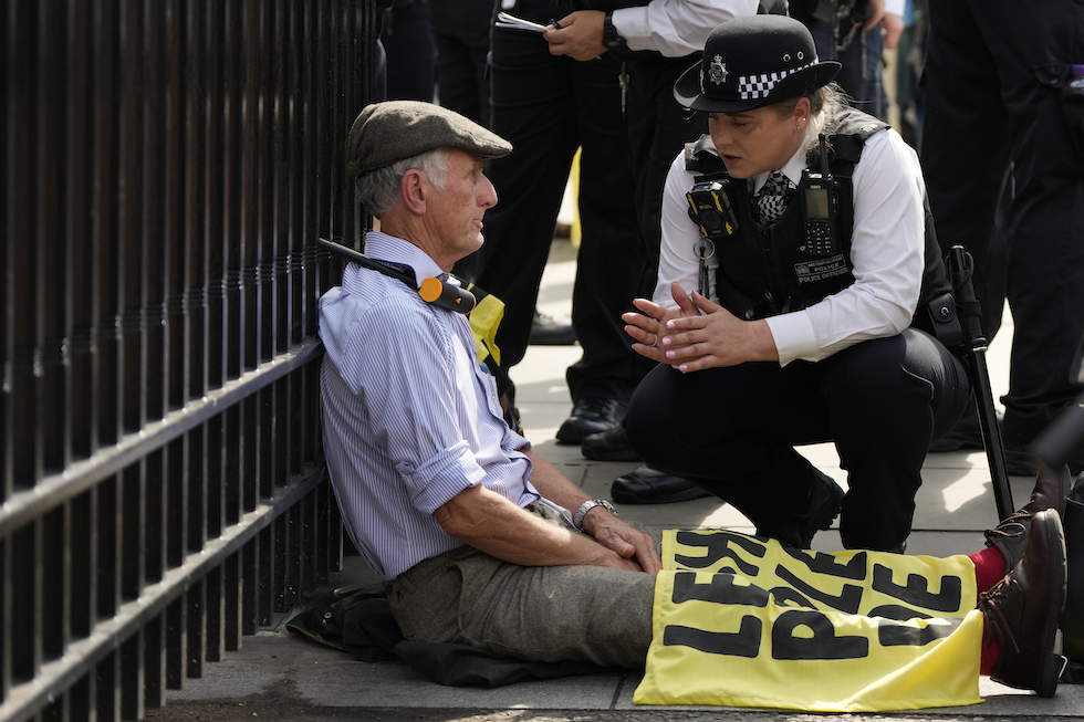 Un membro di Extinction Rebellion incatenatosi per il colo alla cancellata della sede del Parlamento britannico