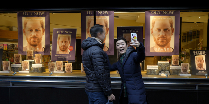 Una donna si scatta un selfie con una vetrina di una libreria di Londra che mostra le copie del libro del principe Harry in vetrina