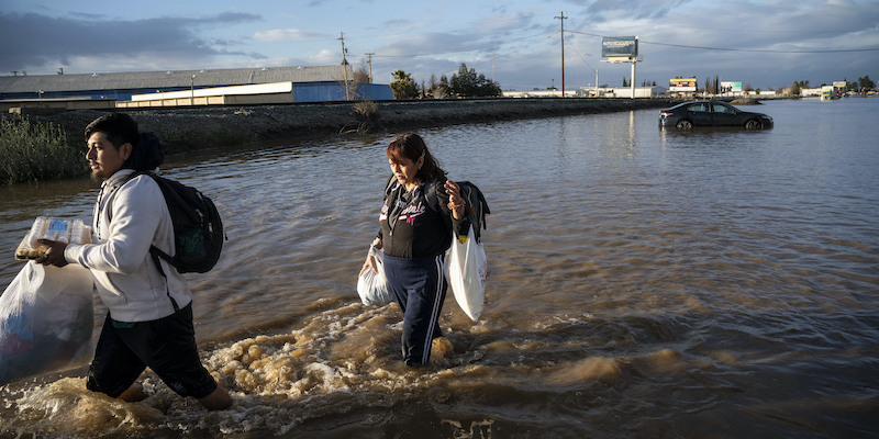 Due persone portano via oggetti dalla propria abitazione a Merced, in California (AP Photo/Noah Berger)