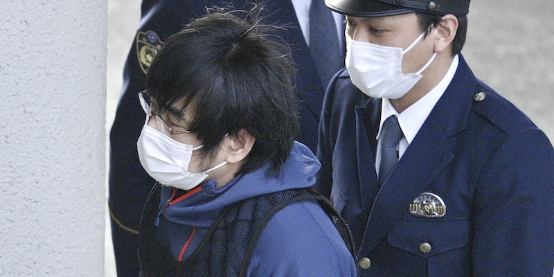 Tetsuya Yamagami entra in una stazione di polizia scortato da un agente (Kyodo News via AP)