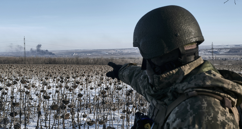 Un soldato ucraino indica il fumo che si alza da Soledar dopo un bombardamento (AP Photo/Libkos)